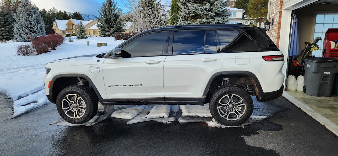 A white Jeep Grand Cherokee with tinted windows in a driveway